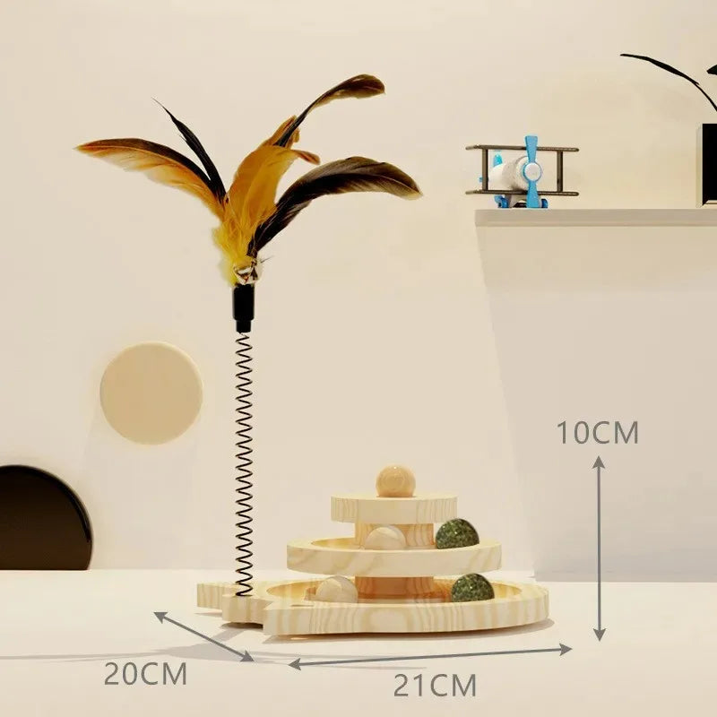 A Triple-Level Wooden Cat Toy Tower with a large yellow feather, a small wooden ball, and a metal spring mechanism, displayed on a table with measurements indicated.