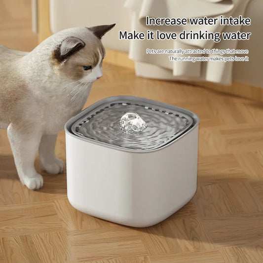 A cat looking at a white AquaPurr Refreshing Cat Water Fountain with water in it, placed on a wooden floor.