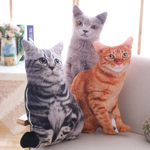 A set of three cat-shaped sofa decoration pillows in black, gray, and orange colors, placed on a sofa in a home environment.