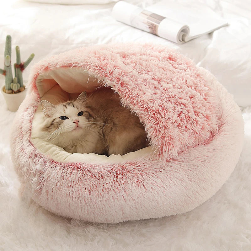 A plush, pink pet mattress designed to look like a cave, with a white cat resting inside.
