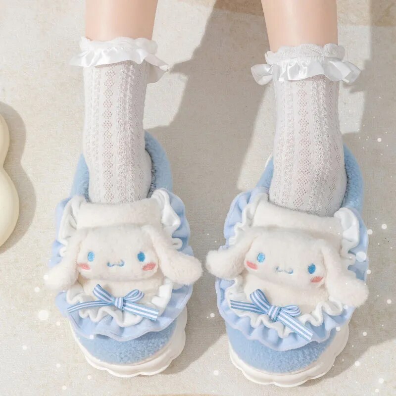 A pair of blue cotton slippers designed to look like cute cat faces, with a plush white fur lining and a bow.