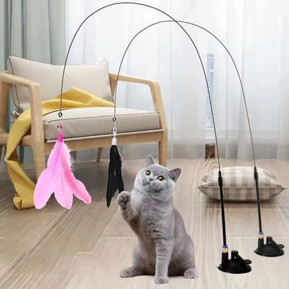 A cat interacting with a pink feather wand toy attached to a suction cup, with detachable feather replacements.