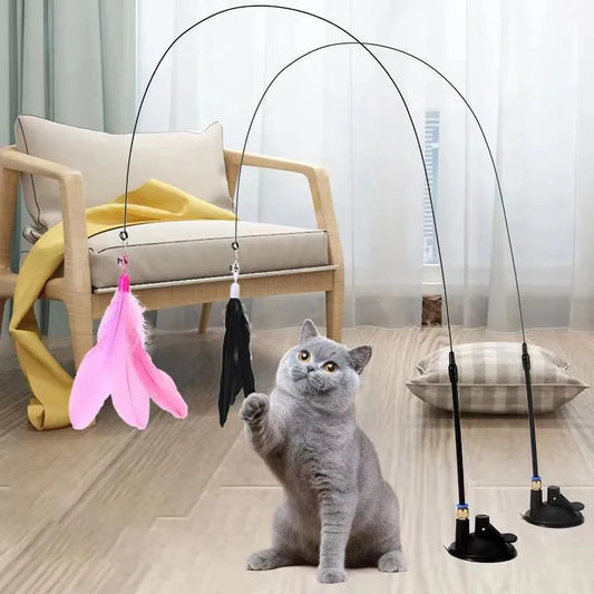 A cat interacting with a pink feather wand toy attached to a suction cup, with detachable feather replacements.