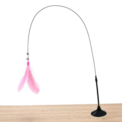A pink cat feather wand toy with a long stem and a suction cup base, attached to a flat surface.