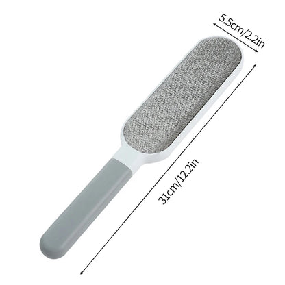 A lint roller with a white handle and a grey roller head, shown being used to remove lint and fur from a person's sweater. There are additional rollers with different colored attachments displayed beside it.