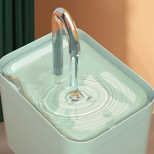 A modern style cat water faucet with a flowing water stream, attached to a transparent pet bowl.