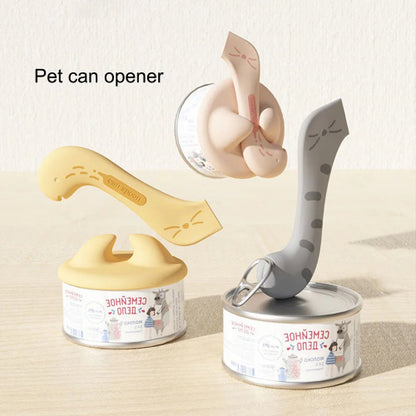 A multifunctional pet spoon and can opener designed to look like a cat. The tool is shown in two colors, beige and gray, with a silicone tip used for opening cans and scooping food.