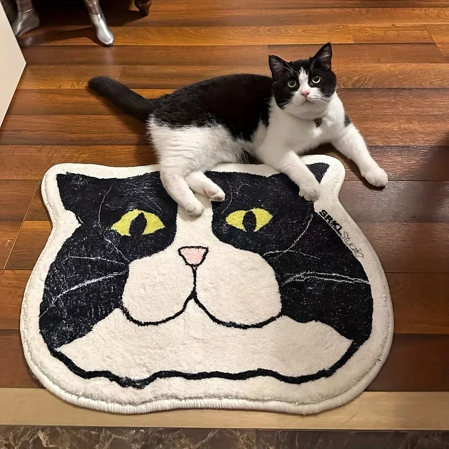 A cat floor mat with a stylized black and white cat face design, with a cat lying on it.