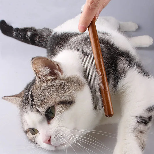 A wooden pet hair remover brush being used on a cat, demonstrating the product's use in grooming pets.