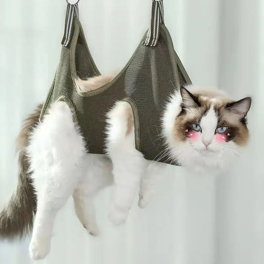 A cat grooming itself while hanging from a pet grooming hammock, which is designed to keep the pet securely suspended in the air.