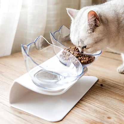 A dual-bowl cat feeder with a white base and clear bowls, with a cat eating from it.