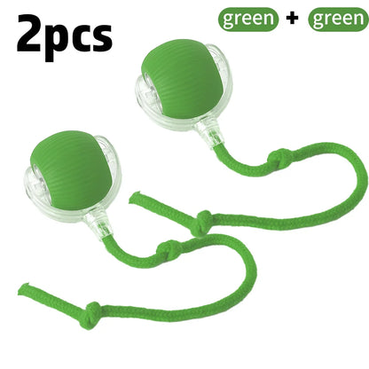 A green and clear rolling ball toy with a faux tail, designed for cats. The toy is on a string, presenting as a playful and interactive pet accessory.