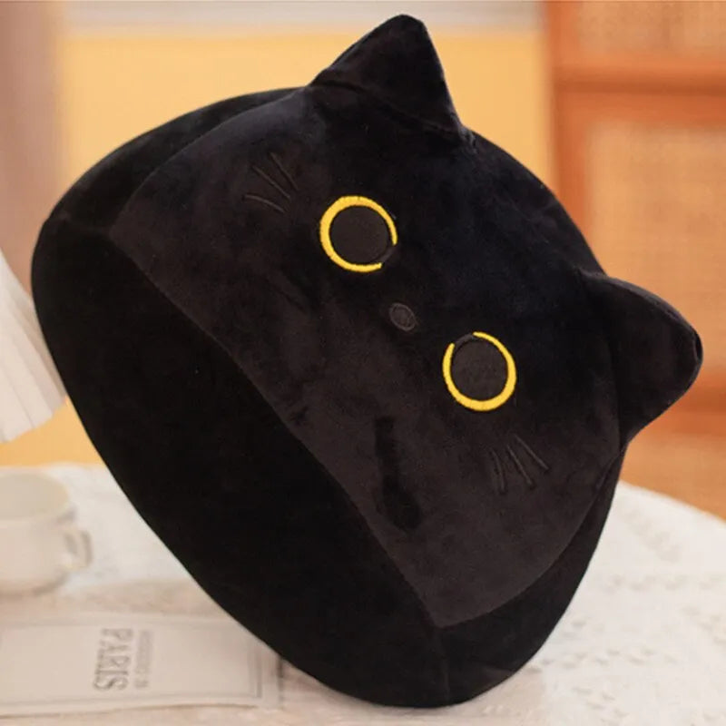 A plush black cushion with a design resembling a cat's face, featuring yellow eyes and ears.