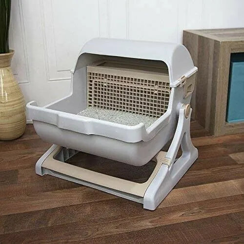 A gray semi-automatic cat litter box with a sifting shovel, situated on a wooden floor.