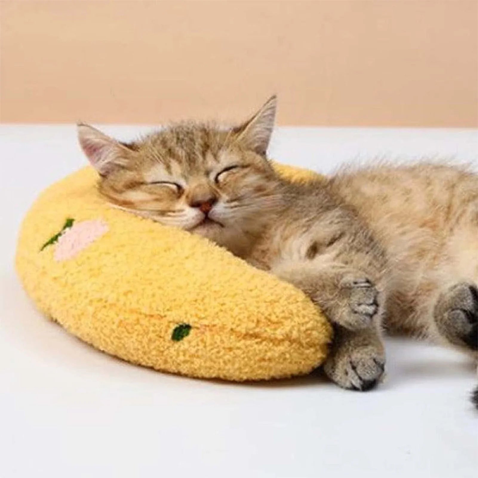 A small cat resting its head on a yellow U-shaped pet pillow.