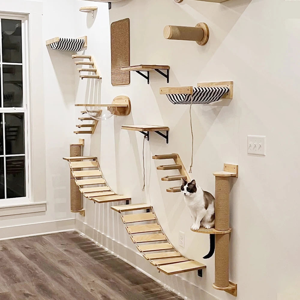 A wall-mounted cat hammock and scratcher with multiple wooden structures attached to a white wall, with a cat sitting on one of the structures.