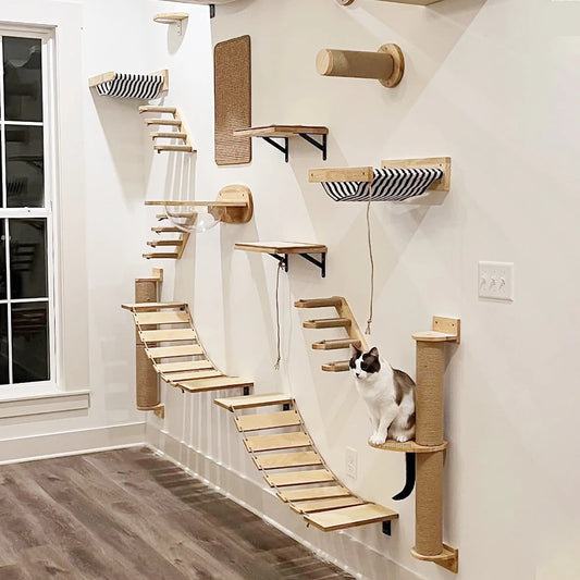 A wall-mounted cat hammock and scratcher with multiple wooden structures attached to a white wall, with a cat sitting on one of the structures.
